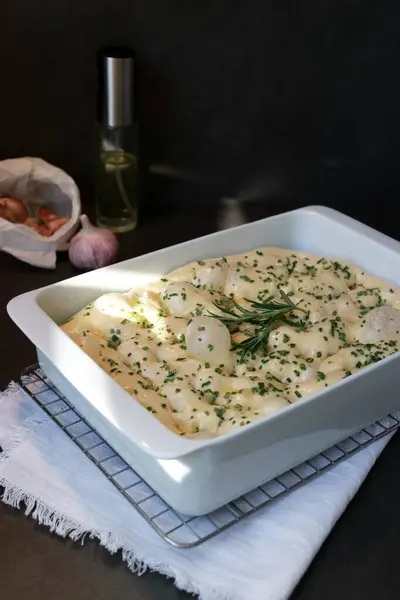 Stock image Raw focaccia dough in white baking dish with garlic rosemary, dark grey table