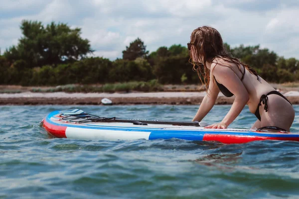 若い女性は海でボードを押しています 健康と自然の概念での生活に適合します — ストック写真