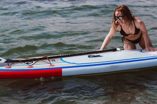 若い女性は海でボードを押しています 健康と自然の概念での生活に適合します — ストック写真