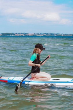 Sarışın, kürek çeken genç bir kadın denizde kürek çekiyor. Sağlıklı ve hayat dolu.. 