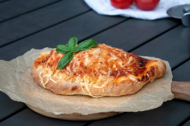 Domates soslu, ahşap tabakta peynirli pizza dilimi. Fotokopi alanı olan gri masa.