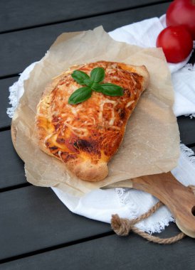 Domates soslu, ahşap tabakta peynirli pizza dilimi. Fotokopi alanı olan gri masa.