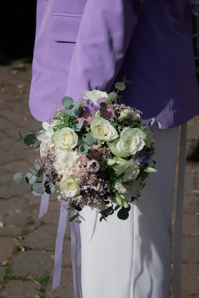 Close up of modern bride holding a wedding bouquet with white and purple flowers. Wedding concept