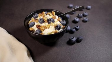 Gri mutfak masasında siyah kasede taze yaban mersinli süzme peynir, protein tatlısı.. 