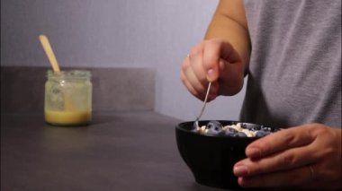 Kadınların elleri siyah kasede taze yaban mersinli süzme peynir karıştırırken, protein tatlısıyla savaşırken.