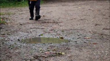 Yürüyen ve parktaki bir su birikintisine atlayan bir çocuğun sonbahar arkaplanı. 