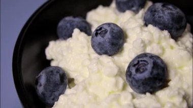 Beyaz arka planda siyah kasede taze yaban mersinli süzme peynirin kapağı, protein tatlısı.. 