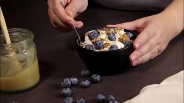 Kadınların elleri siyah kasede taze yaban mersinli süzme peynir karıştırırken, protein tatlısıyla savaşırken.
