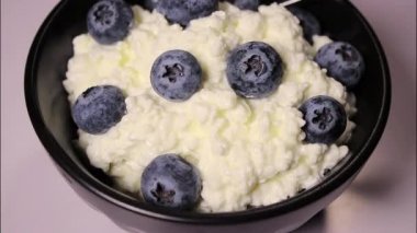 Beyaz arka planda siyah kasede taze yaban mersinli süzme peynirin kapağı, protein tatlısı.. 