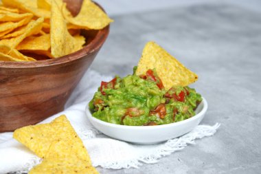 Taze avokado guacamole sosunu tuzlu tortilla cipsi ve gri mermer masaya yakın.