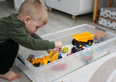 Evde plastik bir kutuda beyaz ev yapımı kinetik kumla oynayan küçük bir çocuk, güzel motor beceriler kavramının gelişimi 