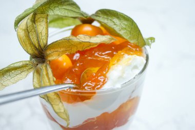 Katmanlı tatlıyı protein yoğurdu ve cam bir kavanozda, mermer masanın üzerinde bitki özü ile kapat. 