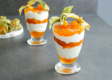 Gri masadaki cam bir kavanozda protein yoğurdu ve bitki özü ile katmanlanmış tatlı. 