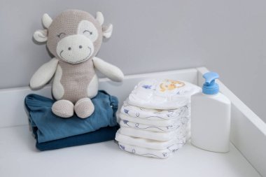 Bir yığın bebek bezi, mavi tulum ve bebek malzemeleri beyaz soyunma masasında, hemşire odasında. 