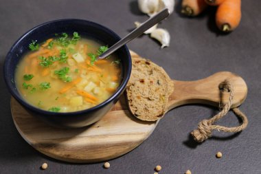 Vejetaryen yeşil bezelye çorbası, zeytinli ekmek dilimleri, gri mutfak masası.