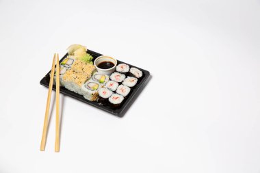 Suşi, siyah bir yemek kutusuna konacak. Beyaz arka planda tahta çubuklar olacak.