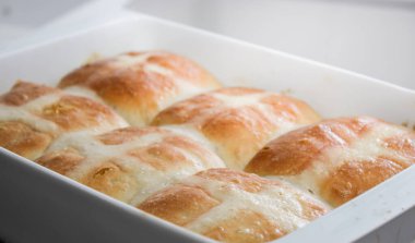 Fırında pişmiş sıcak haç çörekleri, gri mutfak masasında. 