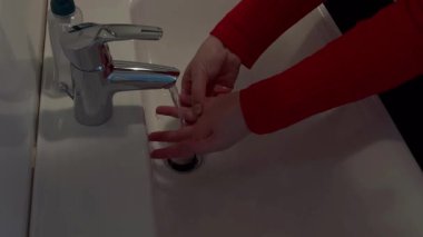 Evdeki banyoda ellerini yıkayan kadına yakın dur.