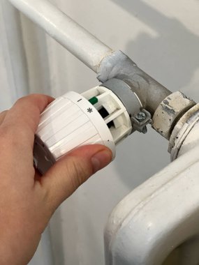 Termostat radyatörünü en soğuk pozisyonda çeviren bir ele yaklaş. Soğuk mevsim konseptinde evlerin ısıtılması
