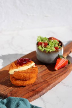 Üzerine kızılcık sosu ve ahşap tabakta taze salata, beyaz mermer masa. 