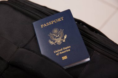 Siyah bir seyahat çantası cebinde, bulanık arka planda bir Amerikan pasaportunu kapat.