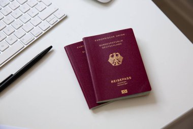 Beyaz masadaki siyah tavalı, klavyesi ve faresi olan bir Alman pasaportunun üst görüntüsü. Yüksek kalite fotoğraf