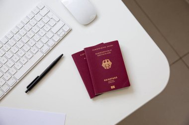 Beyaz masadaki siyah tavalı, klavyesi ve faresi olan bir Alman pasaportunun üst görüntüsü. Yüksek kalite fotoğraf