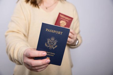 Sarı kazaklı bir kadının elinde Amerikan pasaportu ve boş bir fotokopi odası olan bir Rus pasaportu var. 