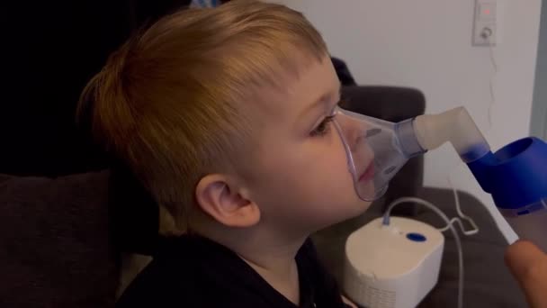 在家里 紧紧地抱着一个吸入面罩呼吸盐水溶液的白人小男孩 — 图库视频影像