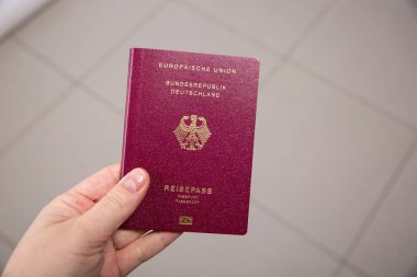 Alman pasaportlu, bulanık arkaplanı olan bir kadın eli.