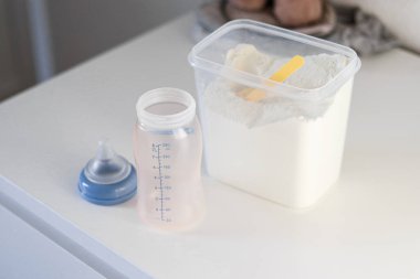Sarı plastik kepçe ve boş beslenme şişesiyle bebekleri beslemek için kuru toz mama formülünün üst görüntüsünü kapatın.
