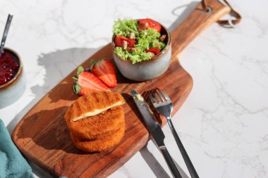 Taze yapılmış ve dilimlenmiş, ahşap tabakta taze salata ve beyaz mermer masa ile peynirli camembert peyniri. 