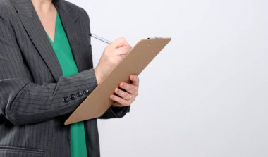 Gri ceketli, gri ceketli genç bir kadının, gri, boş bir stüdyo arka planına yazı yazışının yakın plan fotoğrafı.