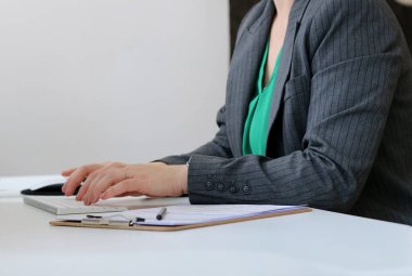 Masada çalışan gri ceketli, bulanık geçmişli, beyaz bir kadının fotoğrafını çek.