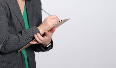 Gri ceketli, gri ceketli genç bir kadının, gri, boş bir stüdyo arka planına yazı yazışının yakın plan fotoğrafı.