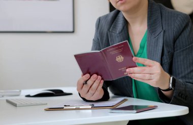 Elinde Alman pasaportu olan beyaz bir kadının fotoğrafını çek ve ofiste vize başvurusu formu doldur.