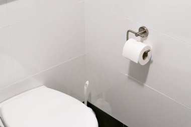 Banyodaki modern bir krom tutacağa asılı beyaz tuvalet kağıdı rulosu, beyaz kiremit duvar 