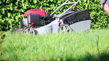 Bahçede güpegündüz yeşil çim biçen, bulanık arka planda bir adamın yakın plan fotoğrafı. 