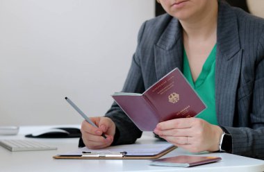 Elinde Alman pasaportu olan beyaz bir kadının fotoğrafını çek ve ofiste vize başvurusu formu doldur.