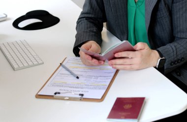 Kafkas bir kadının ofis masasında Alman pasaportu ile vize başvuru formlarını doldurmasının en iyi görüntüsü.