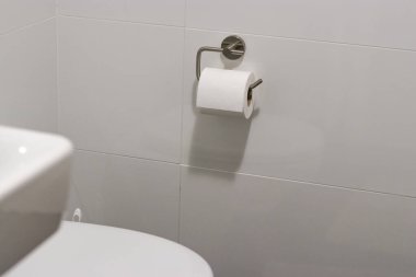 Banyodaki modern bir krom tutacağa asılı beyaz tuvalet kağıdı rulosu, beyaz kiremit duvar 