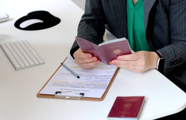 Kafkas bir kadının ofis masasında Alman pasaportu ile vize başvuru formlarını doldurmasının en iyi görüntüsü.