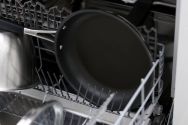 Dolu bir bulaşık makinesinin yanına siyah, temiz bir tava koy.