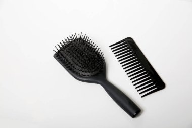 Siyah saç fırçası ve tarakla dolu beyaz masa, baş hijyen konsepti.