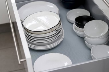 Gri mutfak dolabındaki beyaz tabakları ve diğer tabakları kapat.