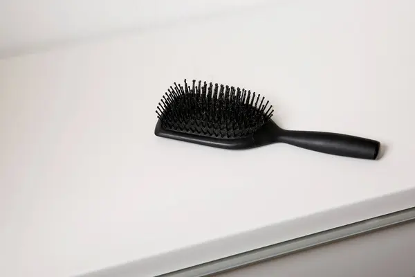 stock image Used black dirty hair brush full of hair on white table background, hair loss problem concept