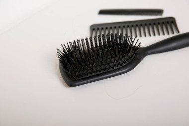 Kirli siyah saç fırçaları ve beyaz masanın üzerinde saç olan taraklar, baş hijyen konsepti