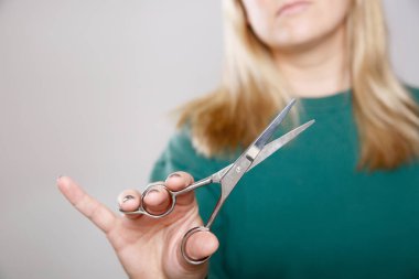 Kadın ellerini makasıyla kapat, arka planda sarı saçlı bir kadın, sarı saçlı bir kadın.. 