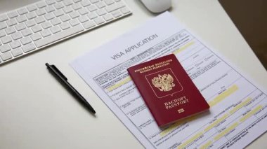 Beyaz ofis masasında Rus pasaportlu bir vize başvuru belgesini kapat