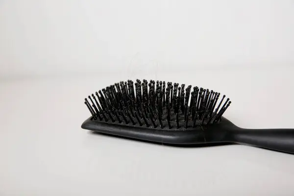 stock image Close up of a black used dirty hair brush full of hair on white table, hair loss problem concept